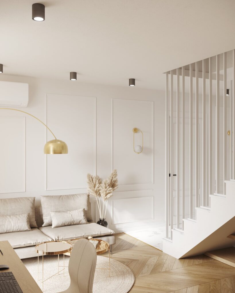 Lounge cu canapea bej lângă pereți albi cu baghete, lampă arcuită și aplică aurie, și o scară albă mascată de bare verticale